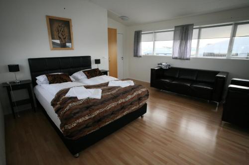 a bedroom with a large bed and a couch at Skýjaborg Apartments in Höfn