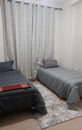 a bedroom with two beds and a curtain at استراحتي in Hajreien