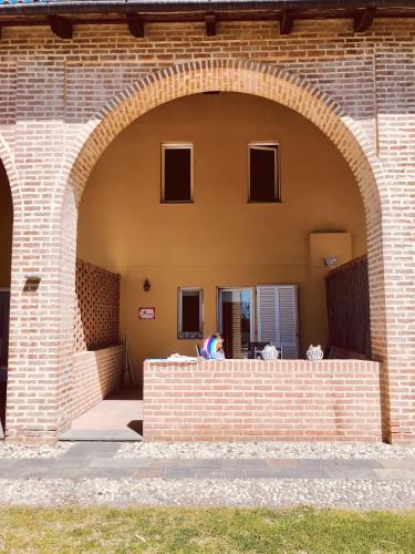 an archway in a brick building with a person sitting on it at Villetta rosso Rubino in Vignale Monferrato