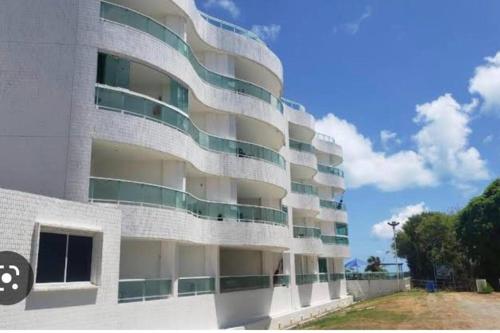 een wit gebouw met groene en witte balkons bij Flat Beira Mar Carapibus in Conde