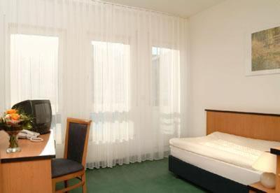 a bedroom with a bed and a desk and a television at Airport-Hotel Stetten in Leinfelden-Echterdingen