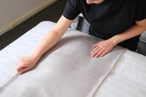 a woman is standing on a bedsheet at Fukuyama Oriental Hotel in Fukuyama
