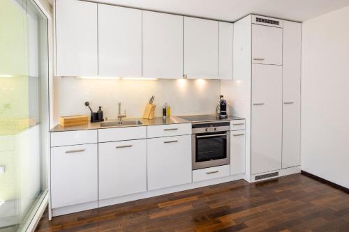 a kitchen with white cabinets and a sink at STAYY Green Oasis near Zurich I free Parking I TV in Dietikon