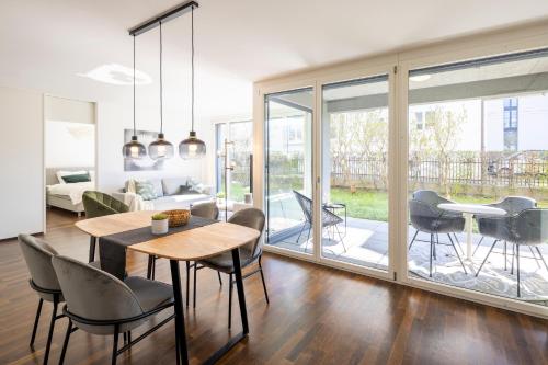 a dining room with a table and chairs and a living room at STAYY Green Oasis near Zurich I free Parking I TV in Dietikon
