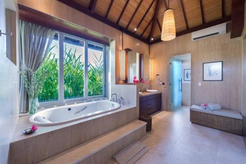 une grande salle de bain avec une baignoire et une grande fenêtre dans l'établissement The Luxe Bali - Luxury 4 Bedroom Cliff Ocean Edge Villa Uluwatu, à Uluwatu