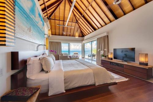 une chambre avec un grand lit et une télévision dans l'établissement The Luxe Bali - Luxury 4 Bedroom Cliff Ocean Edge Villa Uluwatu, à Uluwatu