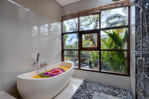 a bathroom with a tub with flowers in it at Kelusa Hill in Ubud