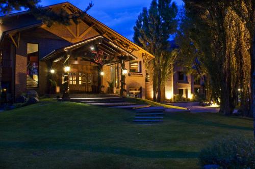 a house with a lit up front yard at night at Hotel Posada Los Alamos in El Calafate