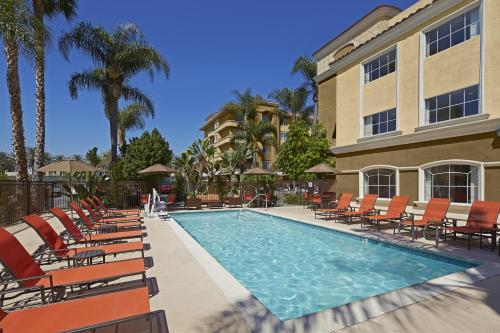 a swimming pool with chairs and a building at Portofino Inn and Suites Anaheim Hotel in Anaheim