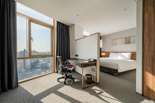 una camera d'albergo con letto, scrivania e finestra di Staz Hotel Ulsan a Ulsan