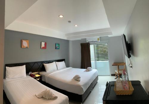 a hotel room with two beds and a television at Nest Boutique Resort in Lat Krabang