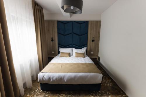 a bedroom with a large bed with a blue headboard at Nedei Hotel&Spa Transalpina in Martinie