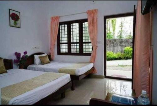 a bedroom with two beds and a large window at Mountain View cottage Mankulam in Munnar