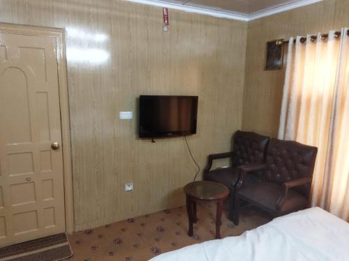 una camera da letto con sedia e TV in una stanza di Chinar Residency a Skardu