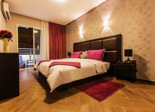 una camera da letto con un grande letto con cuscini rosa di Hotel Swani a Meknès