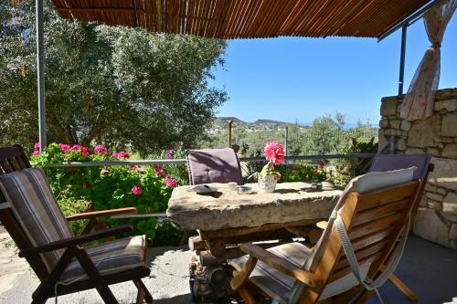a stone table and chairs on a patio with flowers at To Spiti Tou Papa Sto Vouno in Kamilari