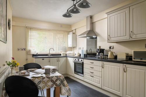 a kitchen with white cabinets and a table with chairs at Miners Cottage in Blaenau-Ffestiniog