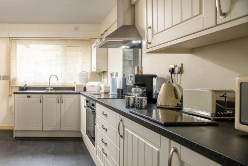 a kitchen with white cabinets and a black counter top at Miners Cottage in Blaenau-Ffestiniog