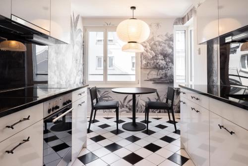 a kitchen with a table and chairs on a checkered floor at EMA House Serviced Apartments Superior Seefeld in Zürich