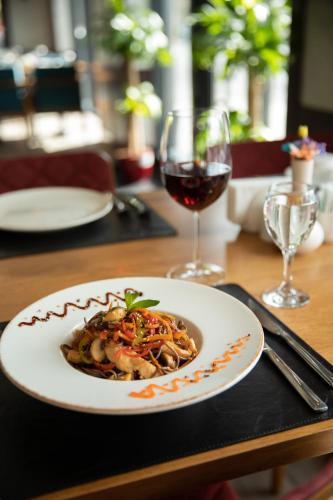 a plate of food on a table with a glass of wine at Premium Hotel Ganja in Ganja