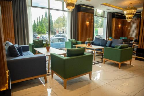 a restaurant with green chairs and tables and windows at Premium Hotel Ganja in Ganja