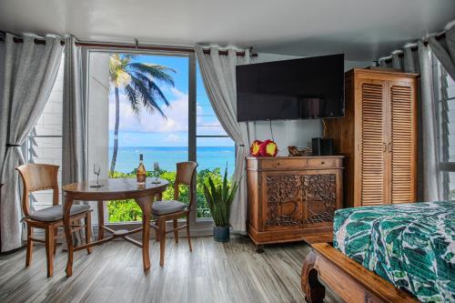 een slaapkamer met een bed en een tafel met uitzicht op de oceaan bij Breezy Beachfront Bali-Style Haven 180 Degree OceanView in Hauula