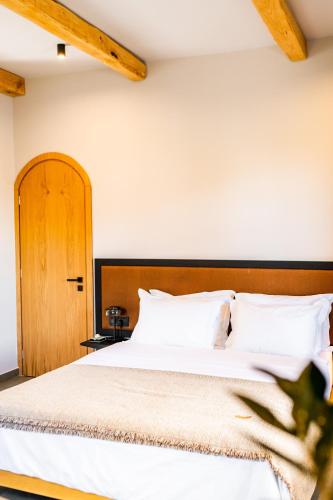 a bedroom with a white bed with a wooden headboard at ANDROMEDA in Kalymnos