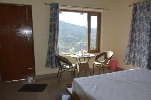 a bedroom with a table and chairs and a window at Saanidhya Homestay in Mukteswar