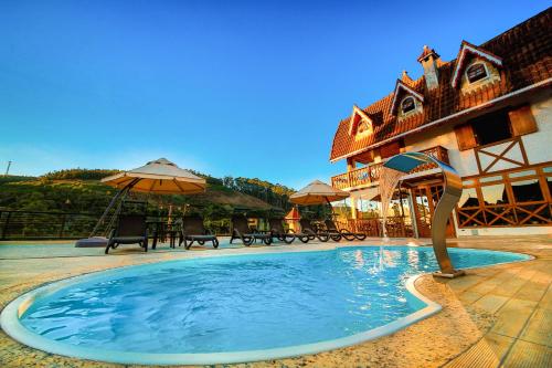 a swimming pool in front of a building with an umbrella at Pousada Palos Verdes in Monte Verde