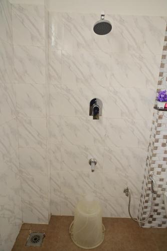 a bathroom with a shower with a white marble wall at Grand Cascade Chennai in Chennai