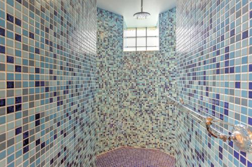 uma casa de banho com paredes de azulejos azuis e uma janela em La Sabliere - Appt à 50m de la plage em Pléneuf-Val-André