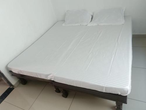 een bed met witte lakens en kussens erop bij ashapura home stay in Navgam