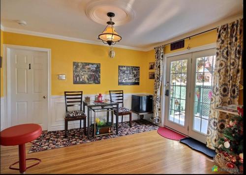 ein Wohnzimmer mit einem Tisch und Stühlen sowie gelben Wänden in der Unterkunft Cozy House B&B in Niagara Falls