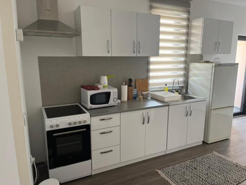 a kitchen with white cabinets and a white microwave at Apartman Paradiso in Pirot