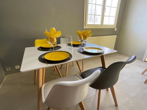einen Esstisch mit 2 Stühlen und einen weißen Tisch mit gelben Platten in der Unterkunft COLORS by Reine du Sud, proche des Grands Buffets in Narbonne