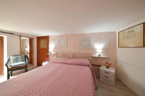 um quarto com uma cama rosa e uma cadeira em Casa Vicolo Saraceno em Ischia