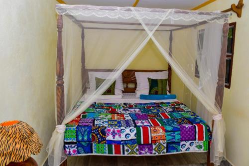 1 dormitorio con 1 cama con dosel en Gästehaus Diani en Diani Beach