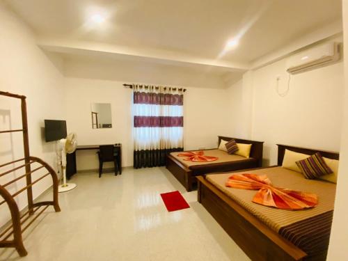 a hotel room with two beds and a desk at Optimum Residencies in Negombo