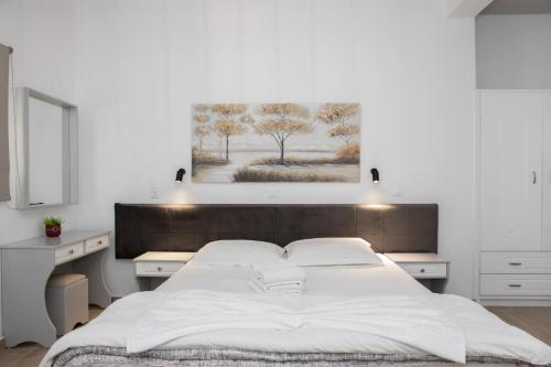 a white bedroom with a large bed and a painting on the wall at Sea Breeze 2 Apartments in Mastichari