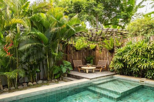 a pool with two chairs and a table next to a fence at Rimba Villas Gili Air in Gili Air