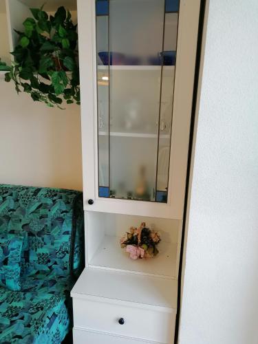 a white cabinet with a mirror and flowers in it at Mare Verde Alloggio con terrazza in San Bartolomeo al Mare