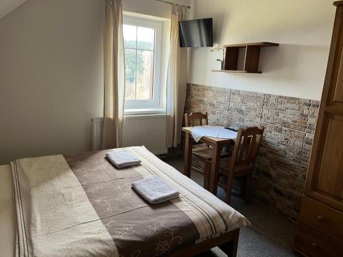 a bedroom with a bed and a table and a window at Na Planýrce in Paseky nad Jizerou