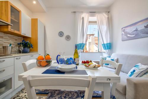 een keuken en een woonkamer met een witte tafel en stoelen bij Casa Vacanze San Michele in Alghero