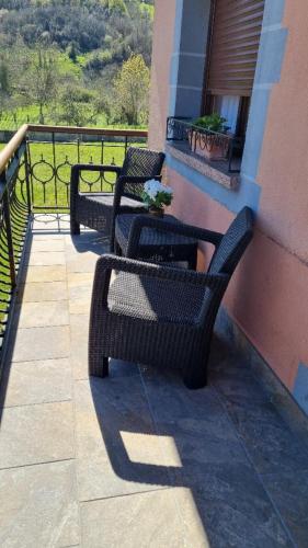 two black chairs and a table on a balcony at La casa de Carolina in Onís