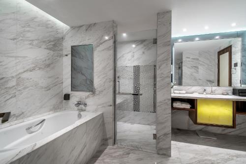 a bathroom with a tub and a sink and a shower at Suning Universal Hotel ALL-SUITES in Nanjing