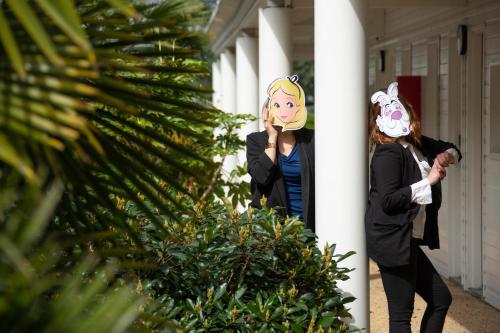 Deux femmes marchent dans un couloir avec une plante dans l'établissement Hôtel Confort Le Moulin Rouge, à Terrasson