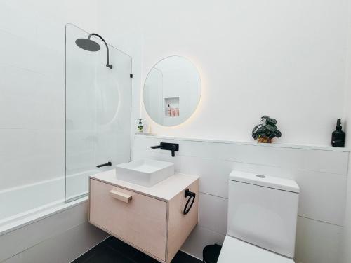 a white bathroom with a sink and a mirror at Sea Haven, A Rye Coastal Retreat! in Rye