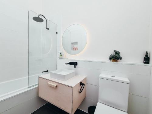 a white bathroom with a sink and a mirror at Sea Haven in Rye