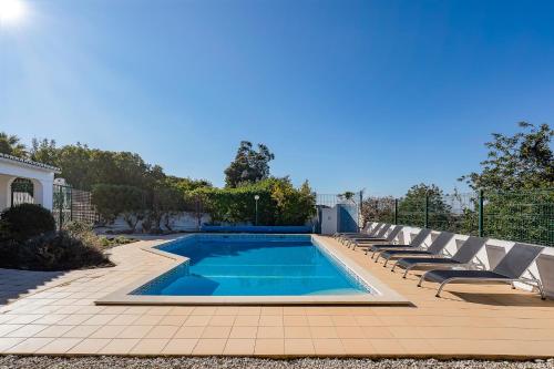 a swimming pool with lounge chairs next to a house at Casa Branca in Estômbar