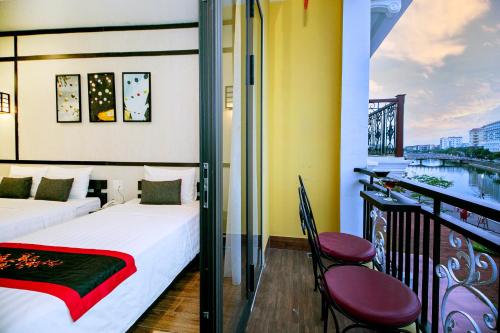 een hotelkamer met een balkon met een bed en stoelen bij Hoi An Riverland Villa - Hoi An Center in Hội An